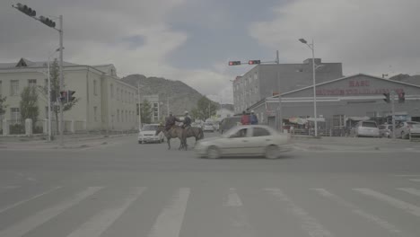 Jinetes-Cruzando-Una-Carretera-Con-Tráfico-En-Una-Ciudad-De-Mongolia.